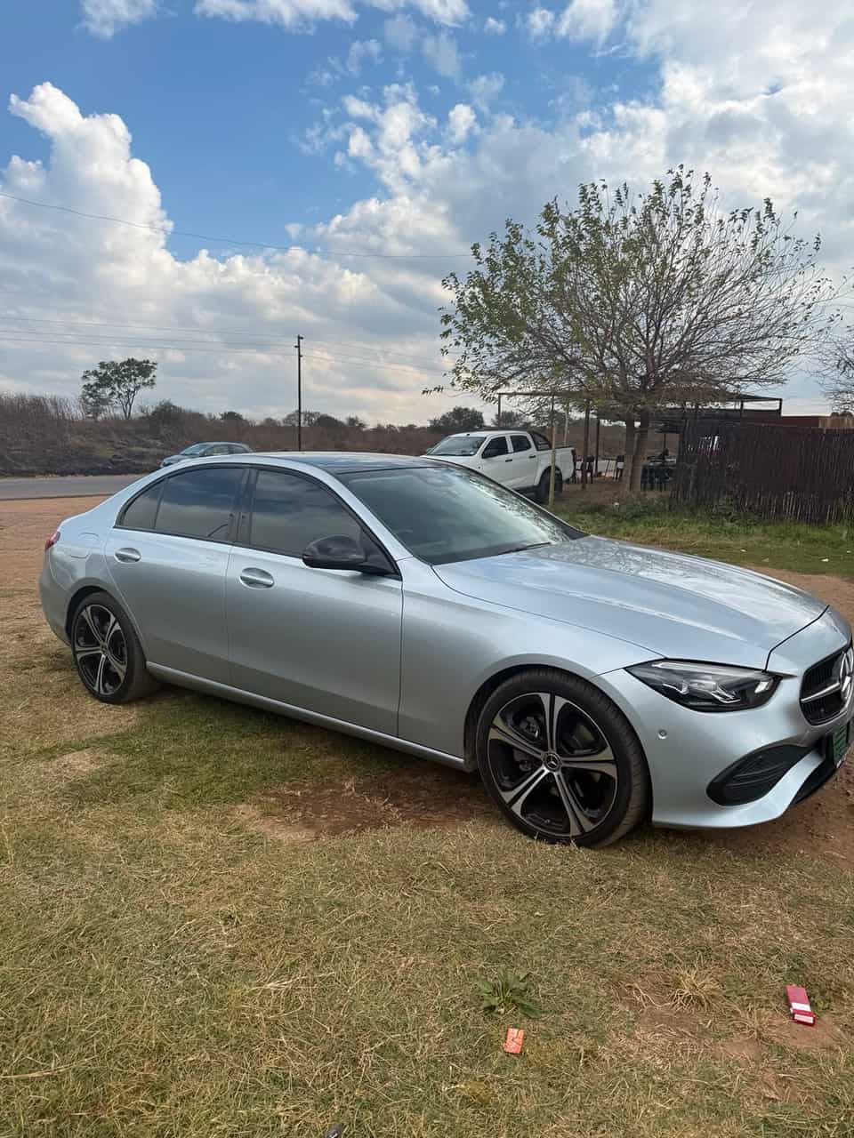 Side profile of the silver Mercedes under a big cumulus sky