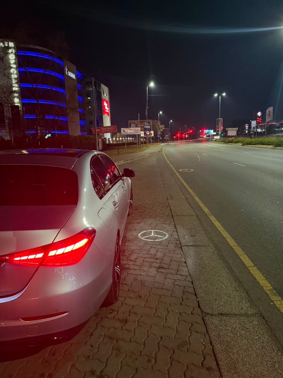 The lit taillight bar of the Mercedes beside an empty dual carriageway at night